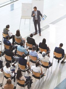 A man, standing, delivers a Competitive Intelligence Introductory Workshop